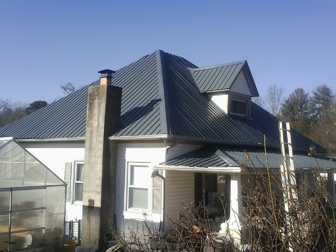 Dark blue standing seam metal roof on a white farmhouse with dormer — Slate & Tile Roof Repair by Roofing Brothers in Mahwah