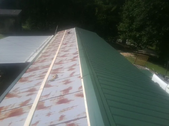 Old rusted panels beside newly installed green metal roofing — Wind Damage Roof Repair by Roofing Brothers in Mahwah