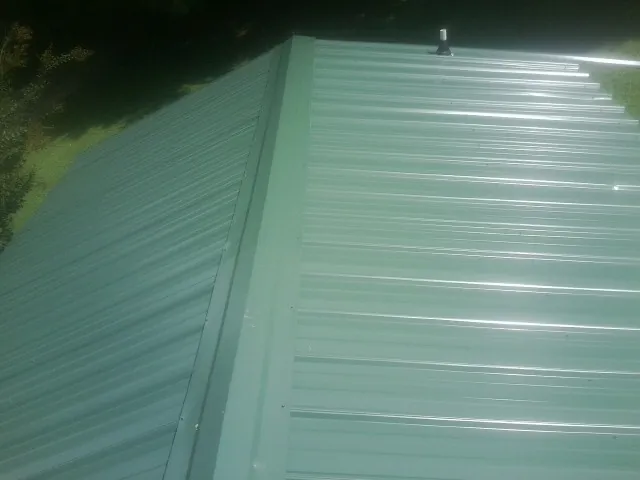 New green metal panels meeting at the ridge of a roof — Flat Roof Repair work by our crew in Mahwah