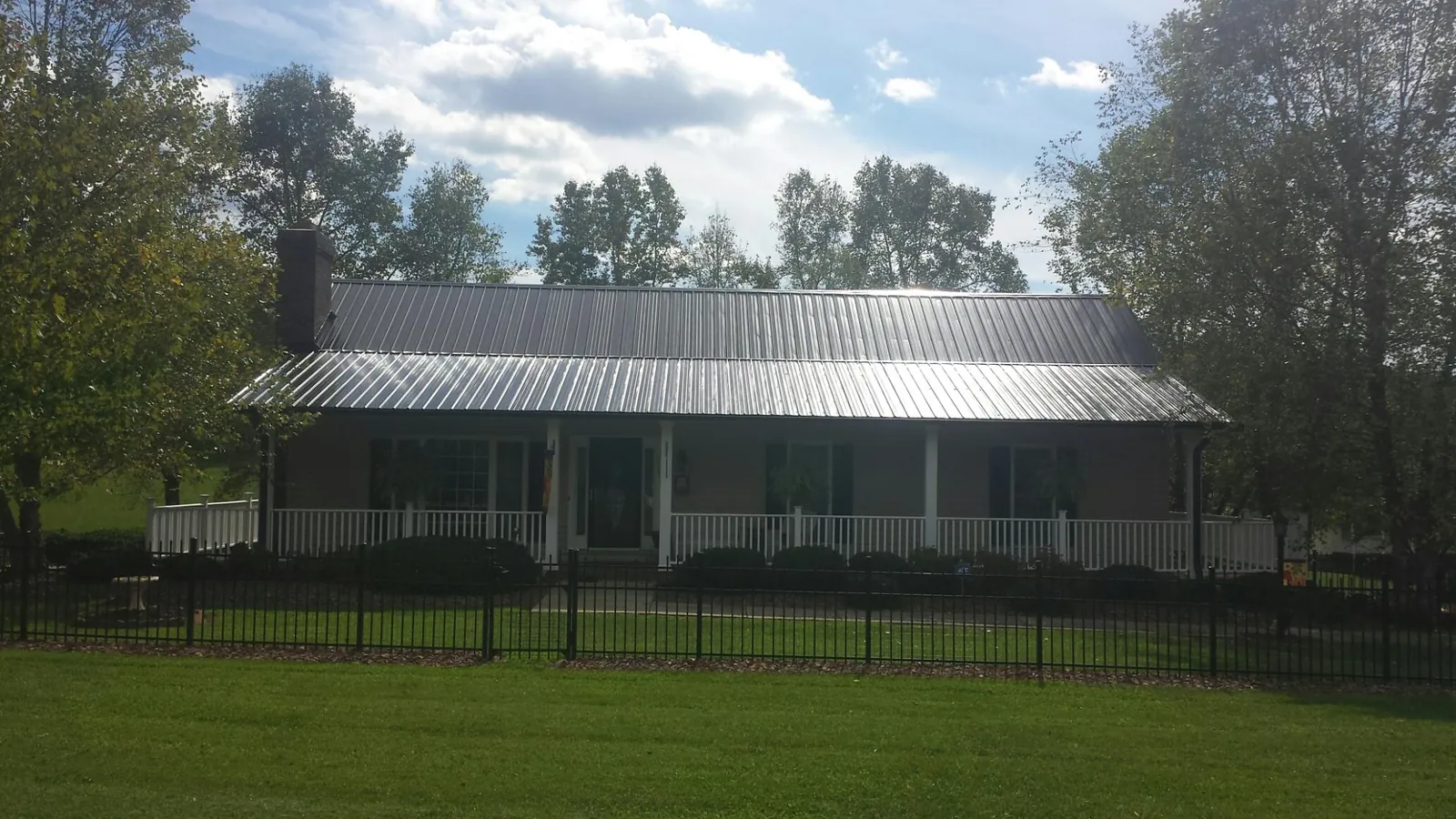 Gray metal roof on a brick ranch with a full width front porch in Mahwah