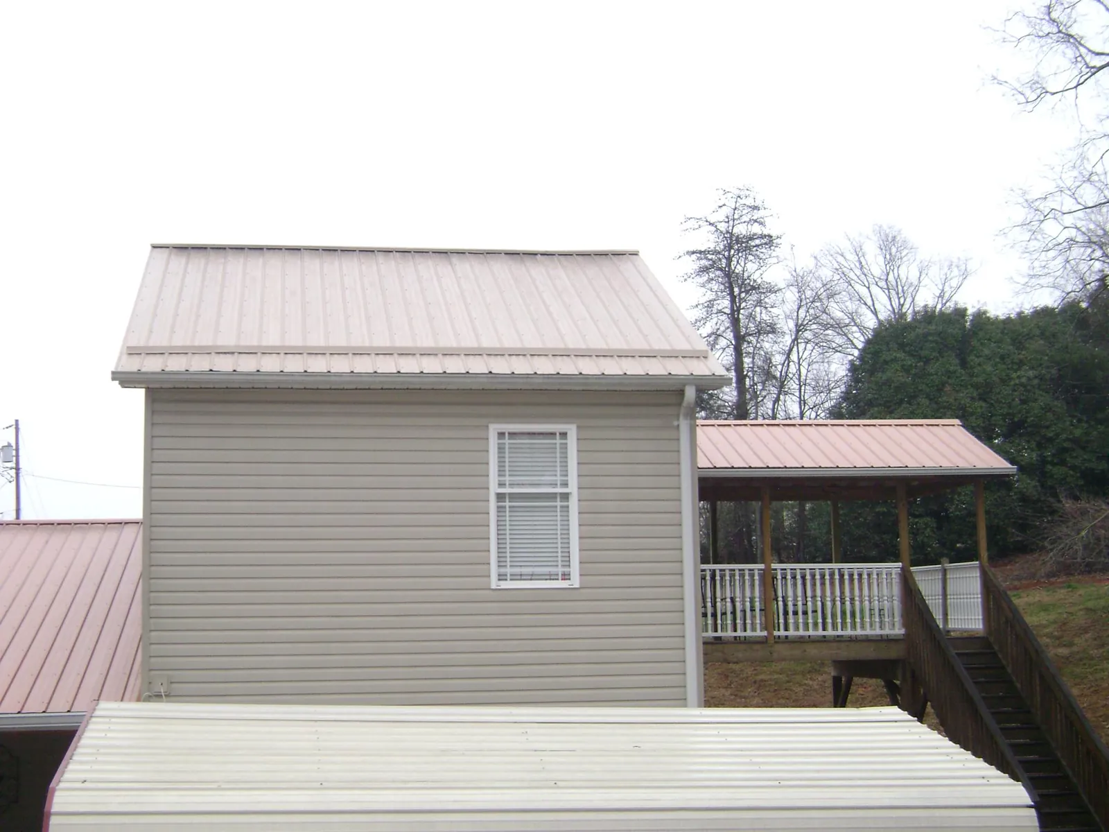 Tan metal roofs on a two story addition and attached porch, from a Roof Replacement job in Mahwah