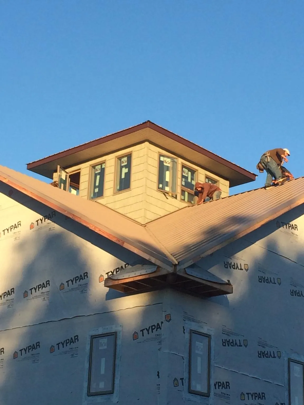 Roofers working around a rooftop cupola on a new metal roof at sunset — Roof Waterproofing in Mahwah by Roofing Brothers